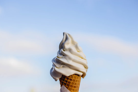 vanilla ice cream cone melting on a sunny say with the sky holding it it to the sky summer day stock photo 
