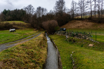 A picturesque landscape view of a river running through the field in a French mountain village
