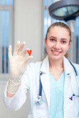 Doctor hands holding a heart, donation and implantation, medic, saving a life. Symbol of saving a life in the hands of a doctor in gloves. copies of the space.