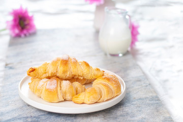 Fresh and beautiful bright breakfast table with croissants, milk on the background with a lot of air and copy space
