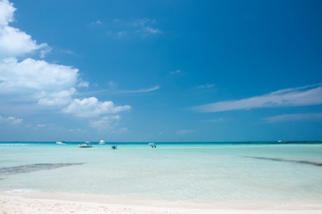 Fototapeta na wymiar Empty beach, small boats in the sea. Idyllic tropical beach in the Caribbean sea of Isla Mujeres, Mexico