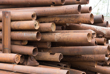 A large pile of old and rusty metal pipes. The pipes are piled up. Background, texture concept.