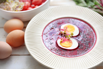 Fototapeta na wymiar Beetroot soup with egg, traditional spring soup. Plate of tasty healthy soup on a wooden table. Vegetable cuisine