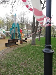 Park, square with playgrounds fenced with ribbons during the coronavirus, quarantine, pandemic. Children on playgrounds, dogs in parks and squares.