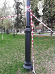 Fototapeta na wymiar Park, square with playgrounds fenced with ribbons during the coronavirus, quarantine, pandemic. Children on playgrounds, dogs in parks and squares.