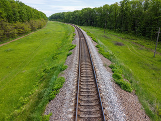 Obraz premium Railway tracks, a road for food that passes through beautiful nature, green grass, trees and spring weather.