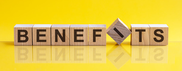 BENEFITS - word from wooden blocks with letters, concept, yellow background.