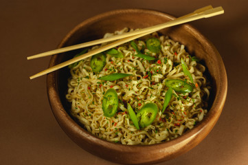 Japanese, Chinese, Asian noodles with hot green pepper on a yellow bed background and a wooden plate