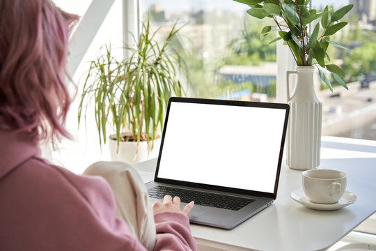 Hipster Teen Girl Student Sit At Kitchen Table Using Laptop Computer Touchpad Mock Up White Blank Monitor Screen Learning Online On Modern Notebook Working From Home Office. Over Shoulder Closeup View