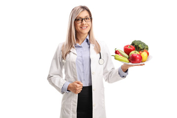 Female doctor holding a plate of fresh fruits and vegetables