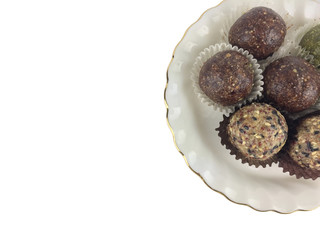 Top view of cutting part of energy balls group which are booster food on white plate in the corner of frame and isolated on white background