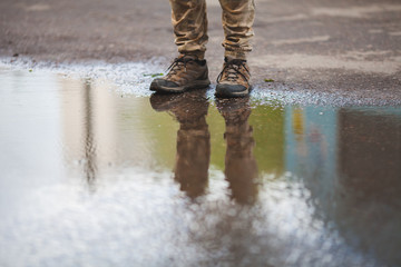 a man in sneakers in puddles with a reflection