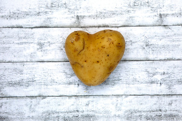 Kartoffel Herz in Herzform aus biologischem Anbau isoliert vor wei&szlig;em Holz Hintergrund.