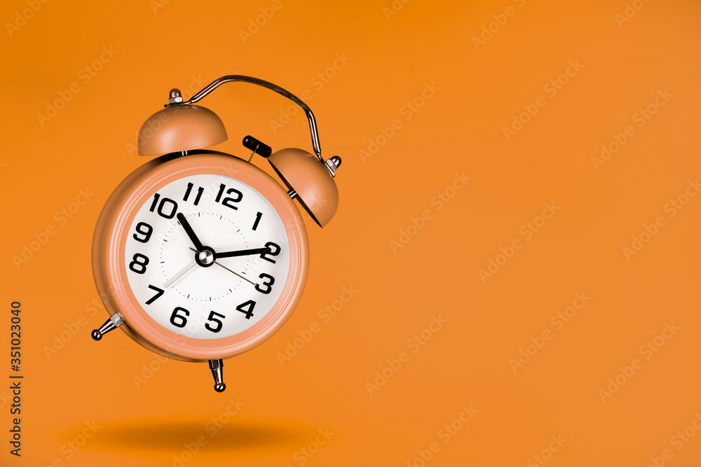 Wall mural orange alarm clock on orange background