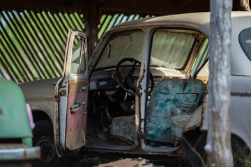an old rusty abandoned car with its doors open