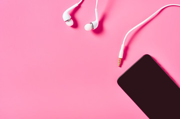 Portable white headphones and smartphone or tablet on pink background. Video calling concept