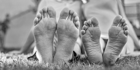Romantic young couple kissing in the garden. Family feet in focus. Feet of a young couple lying on grass at the park.