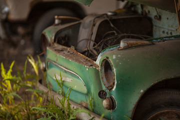 an old rusty green car. without headlights and hood