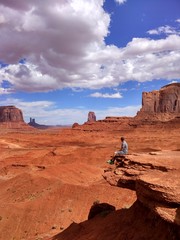 Fototapeta premium A man sitting on a stone at Monument Valley Navajo Tribal Park