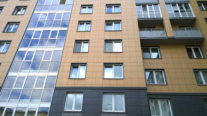 Facade of a new multi-story residential building with windows and balconies. Sale and rental of economy class apartments and comfortable housing. Cityscape. City living. Real estate. Modern office.