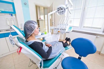 Female patient waiting for dental treatment in a dental chair.