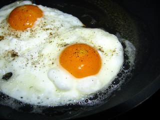 fried eggs with pepper and salt are fried in a pan