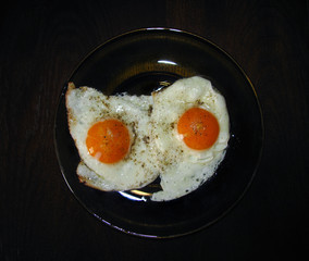 fried eggs with pepper and salt on a plate. The view from the top