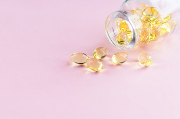 Fototapeta na wymiar Yellow omega-3 capsules from a glass bottle on a pink background. Copyspace for text. Health care, natural, natural supplements. Lifestyle concept