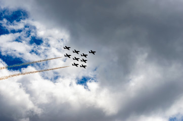 Silhouetted jet fighters in  formation with vapour trails