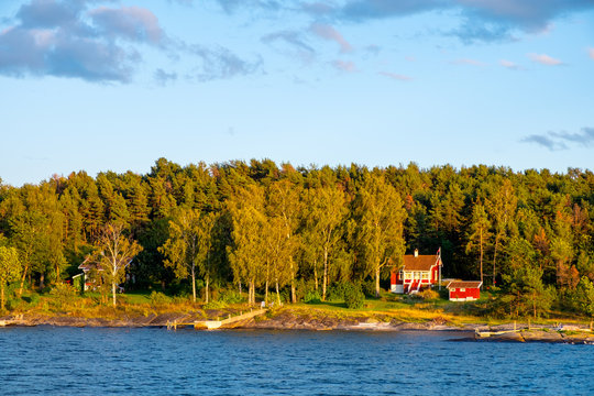 Panoramic sunset view of Lindoya island on Oslofjord harbor with summer cabin houses at wooded shoreline in early autumn near Oslo, Norway