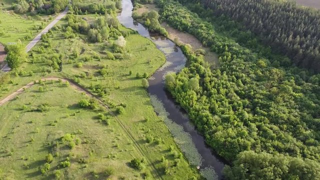 Landscape of the river that stretches through the valley, the evening sun and green grass
