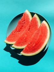 Sliced watermelon on turquoise dish on turquoise background. Watermelon slice. Summer concept. Flat lay, top view, copy space