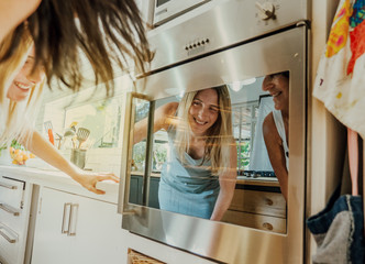 Young woman and mother looking in oven at rising scones