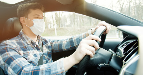 Man driving car in medical mask during an epidemic.