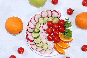 Vegetable salad on a light table, the concept of detox diet, healthy and natural food. Radishes, cucumbers, tomatoes and lemon contribute to improving metabolism and losing weight. Flat lay, 