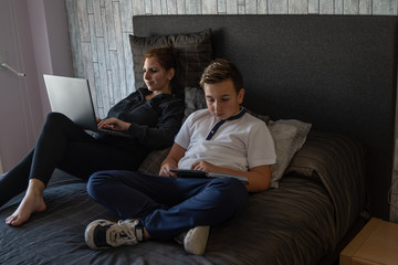 Fototapeta premium mother and son work lying in bed at home because of confinement caused by covid disease 19