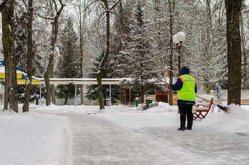 snow storm in the city. Roads and sidewalks covered with snow. Worker shovel clears snow. Bad...