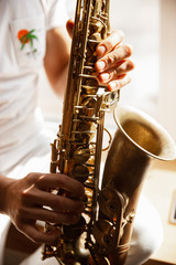 Obraz premium Caucasian musician playing saxophone during online concert at home isolated and quarantined. Using camera, laptop, streaming, recording courses. Concept of art, support, music, hobby, education.
