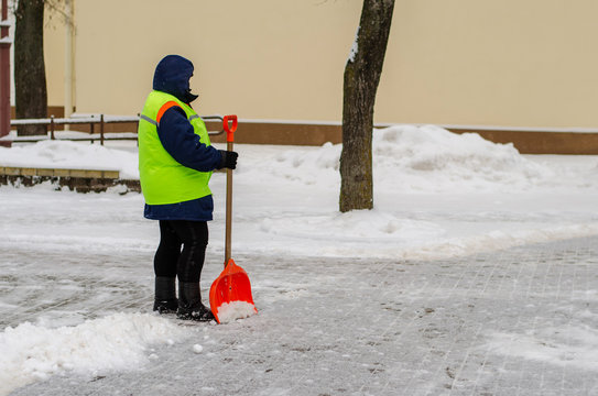 Snow Storm In The City. Roads And Sidewalks Covered With Snow. Worker Shovel Clears Snow. Bad Winter Weather. Street Cleaning After Snowstorm.