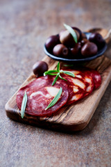 Sliced chorizo with fresh rosemary on rustic background. Close up.