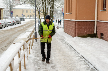 snow storm in the city. Roads and sidewalks covered with snow. Worker shovel clears snow. Bad...