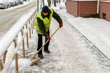 snow storm in the city. Roads and sidewalks covered with snow. Worker shovel clears snow. Bad winter weather. Street cleaning after snowstorm.