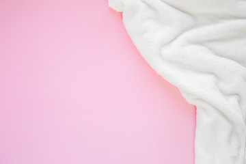 Flat lay white fluffy plaid on a pink background with copy spase. Cozy staing home concept. Top view