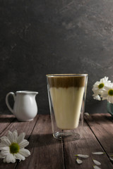 Korean traditional drink dalgona coffee in a tall glass on a wooden background, trend 2020, vertical orientation