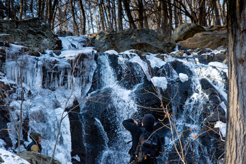 A photographer captures a roaring winter waterfall