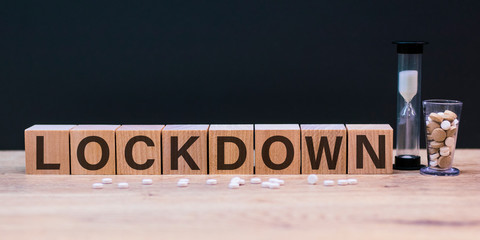 Wooden block has text Lockdown on wooden and dark background. Concept Lockdown covid-19.