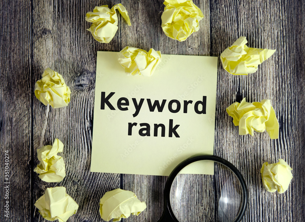 Poster keyword rank - text on yellow note sheets on a dark wooden background with crumpled sheets and a mag