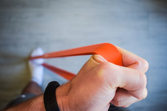 Mano de hombre estirando banda el&aacute;stica para hacer ejercicio en casa