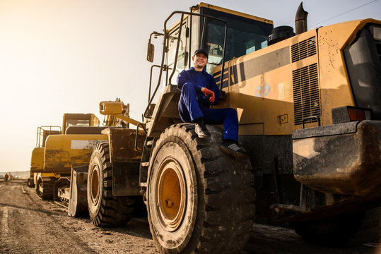 young man contractor builder is sitting on the bulldozer wheel