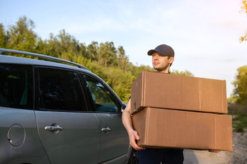 Young man courier holding a paper box